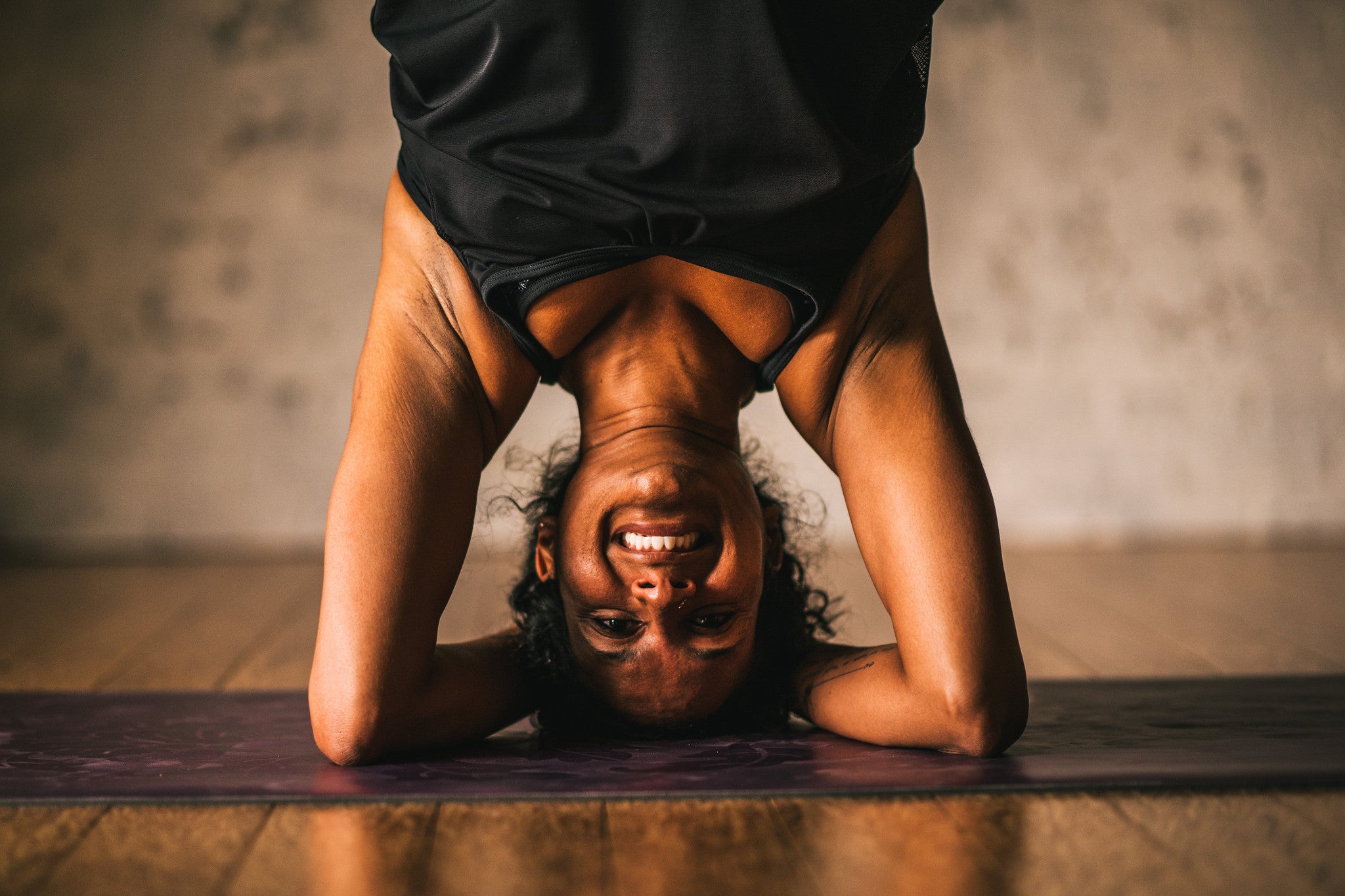 Woman in blank tank top does headstand on yoga mat