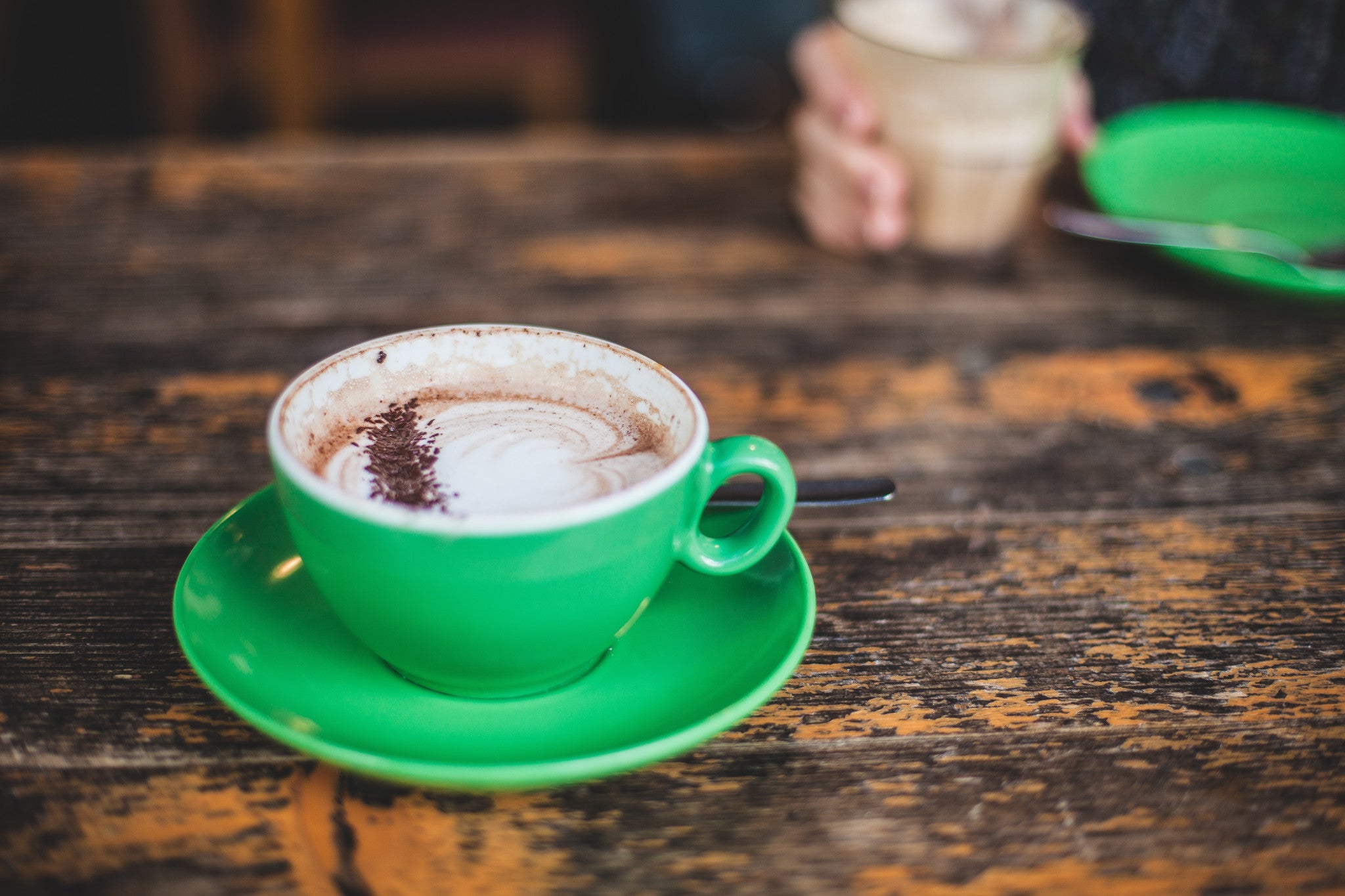 Green coffee mug filled with coffee.