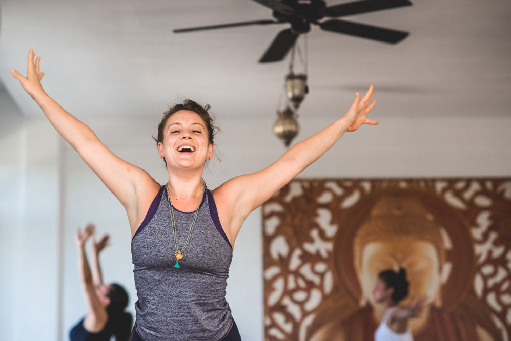 Woman in yoga studio with arms outstretched 
