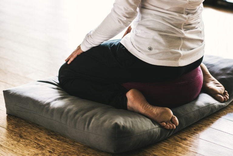 Person sitting on meditation cushions 