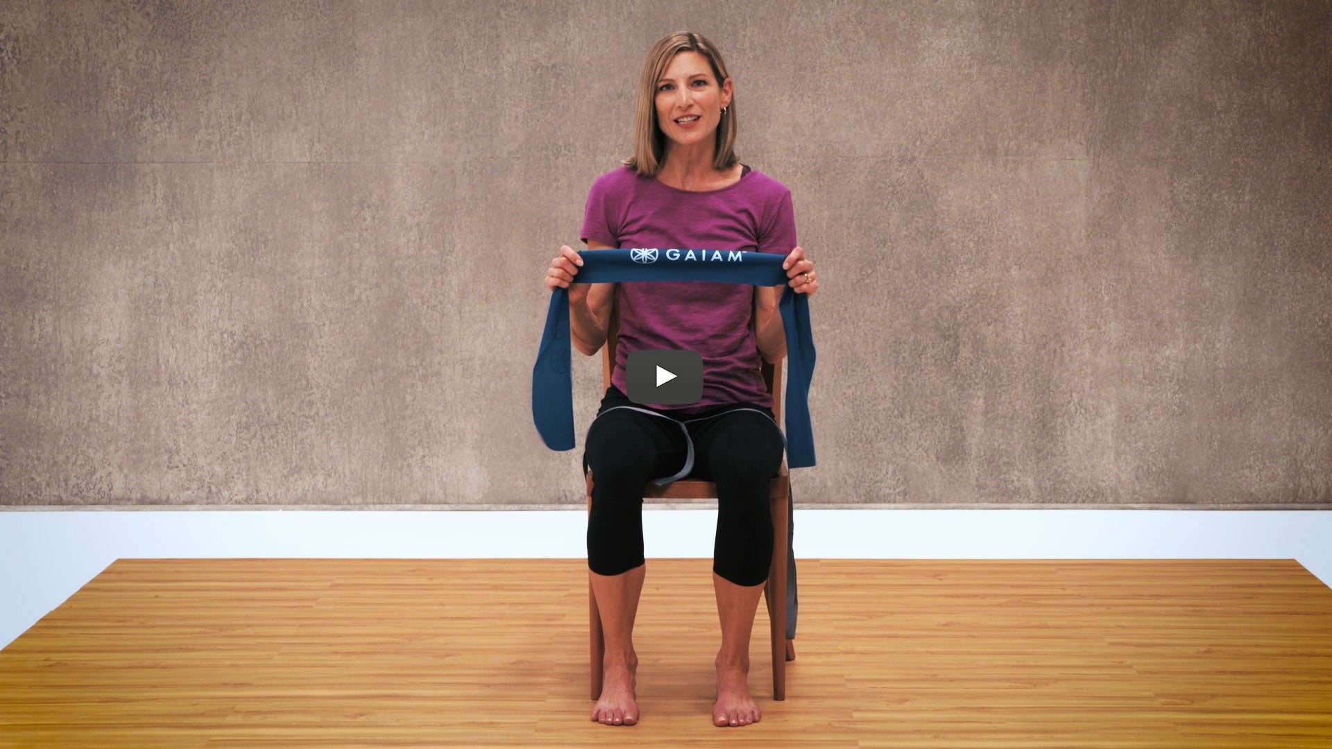 woman sits in chair with gaiam flexibility band