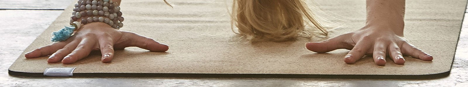 Woman's hands on a cork yoga mat.