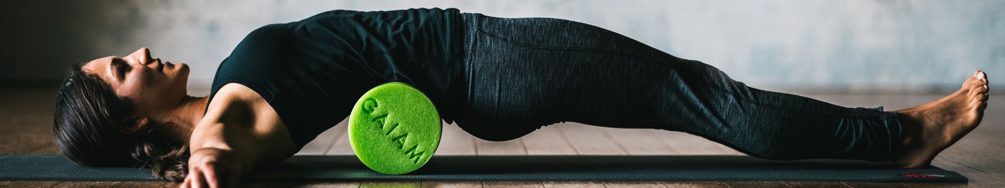 woman rolling her lower back on green foam roller